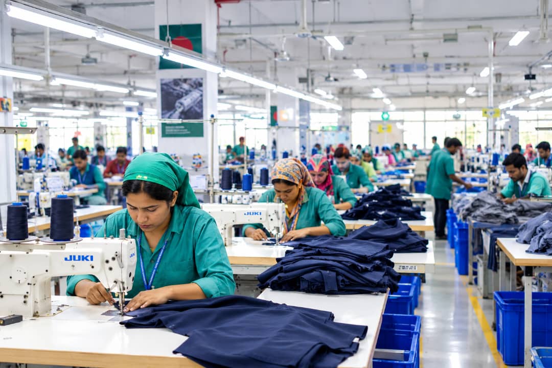 Garment sewing floor inside a factory in Bangladesh, with workers stitching finished apparel on production lines