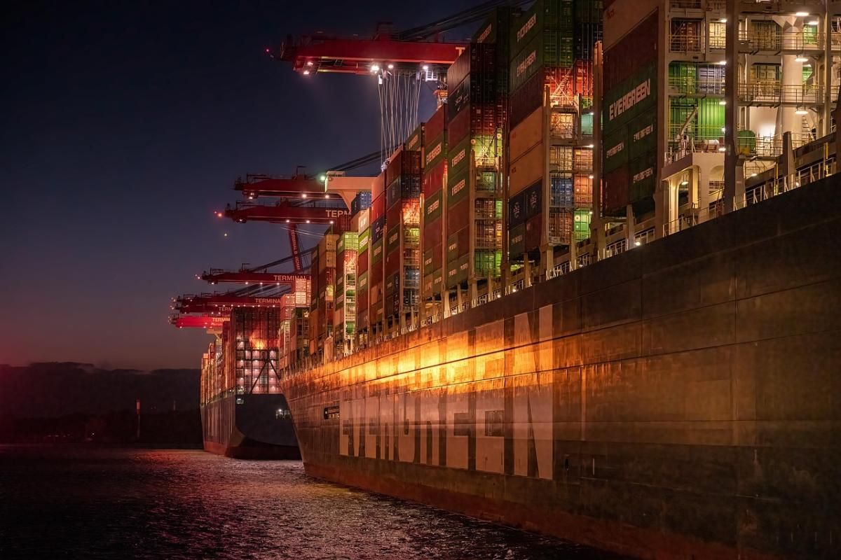 Illuminated shipping port at night with a cargo vessel docked, part of Texlora International's global logistics network